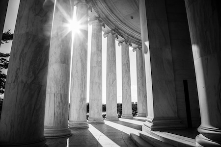 Marble courthouse columns with sunlight shining through the pillars.